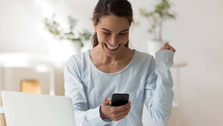 una mujer feliz en su teléfono solicitando un préstamo